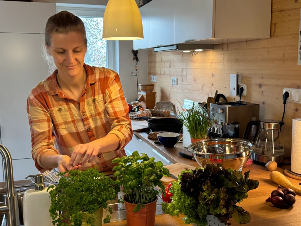 Anja bereitet in der Küche frischen Salat mit Kräutern zu