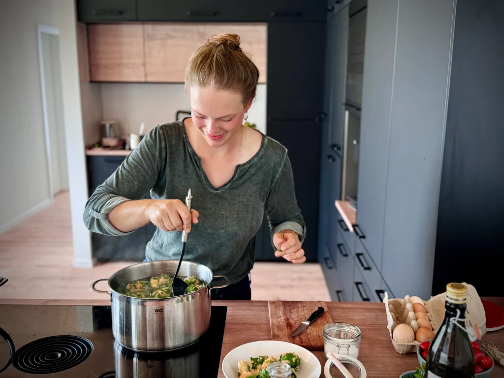 Elena kocht saisonales Gemüsegericht am Herd in moderner Küche mit frischen Zutaten